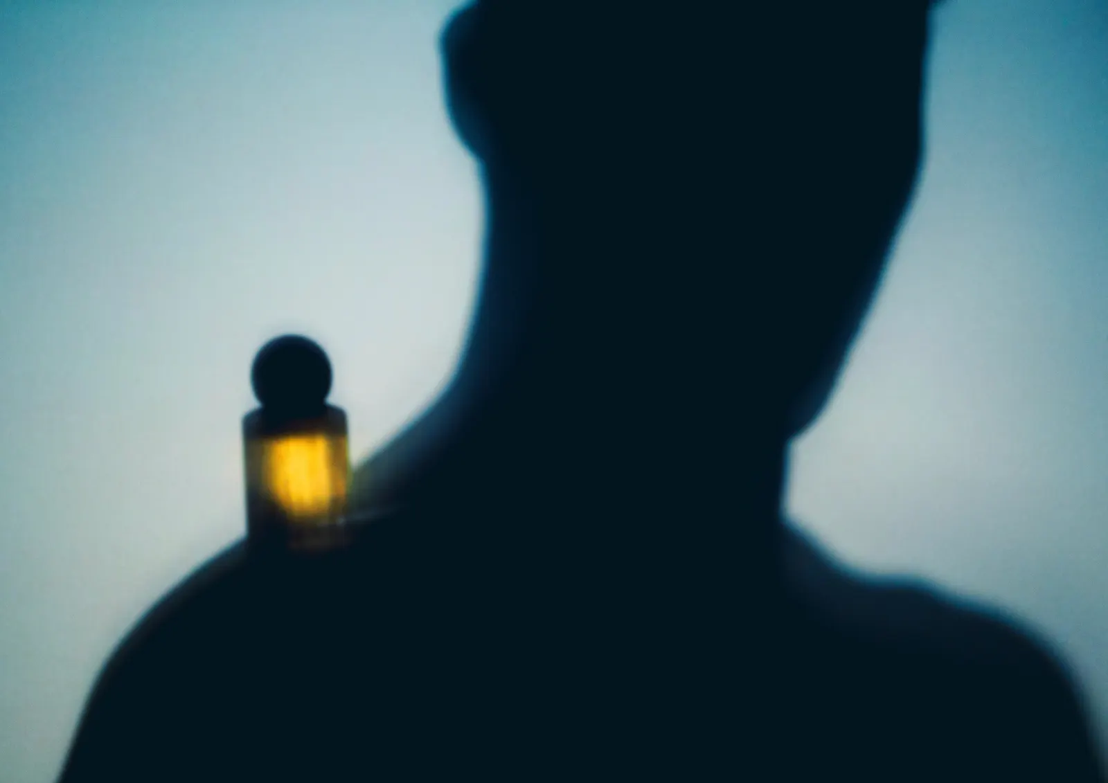 Silhouette with a glowing perfume bottle